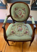 Front view of vintage wooden chair with needlepoint upholstery on seat and back