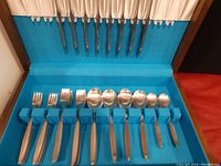 Boxed set display showing knives held in upper section and forks and spoons in blue foam holder.