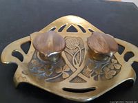 Top view of the brass double inkwell showing floral engravings and two closed lids with patina.