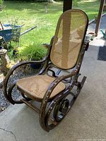 Side angle showing curved bentwood rockers and armrests with cane seat and back.