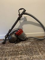 Side view of Dyson Ball vacuum with hose and handle extended, showing spherical ball and dust container.