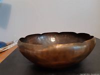 Side view showing the hammered texture and scalloped edge of the copper bowl.