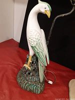 Close-up photo of the Italian pottery bird lamp base showing the colorful bird perched on textured green and brown base.