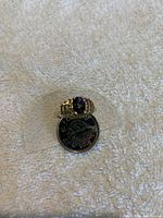 Front view showing oval mystic topaz center stone and surrounding diamonds with Canadian quarter for size scale.