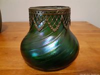 Front view of green glass vase with spiral twisted body and ormolu brass collar featuring lace motif.