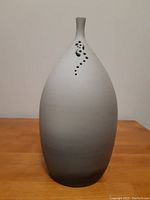 Front view of the egg-shaped art pottery vase showing the gradual color gradient from black to white and the decorative holes near the top.