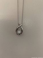 Front view of vintage sterling silver pendant necklace showing teardrop-shaped frame and central sparkling stone that jiggles freely.