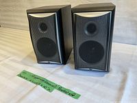 Front view of both Angstrong coaxial bookshelf speakers with black grille and woodgrain finish.