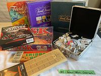 Photo showing lot contents including four Trivial Pursuit editions, Risk, Yahtzee, dominoes in metal case, two wooden cribbage boards.