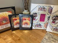 Overview of all five photo frames, three black float frames and two gold/white collage frames still in shrink wrap packaging on the floor.