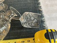 Pinwheel pattern crystal wine glass laying next to measuring tape showing length approximately 7.5 inches