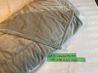 Folded grey weighted blanket showing quilted pattern and soft fabric texture, placed on a white bedspread.