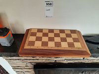Wooden chess board with alternating stained squares and edge notation from front angle