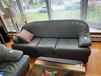 Photo of the entire black leather 3-seater couch with two cushions, angled view showing condition and size.