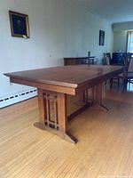 Side view of rectangular table with two trestle bases and cherry wood finish