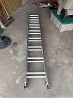 Full length view of aluminum extension ladder, unextended, showing rectangular rungs and rails.