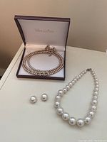 Photo of Volante Collection double-strand pearl necklace with rhinestone details in jewelry box and separate white pearl necklace with matching stud earrings.