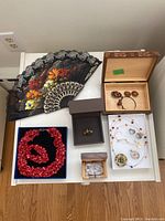 Top view of assorted jewelry items and black decorative fan with floral embroidery