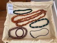 Photo of six necklaces and one bangle bracelet laid on cloth background.