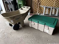 View of Easy Rower plastic wheelbarrow and outdoor storage box next to each other in garage.
