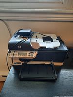 Front view of HP OfficeJet J4680 printer showing paper tray extended and power cable attached.