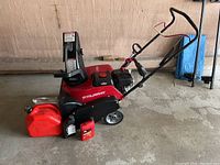 Full view of red Murray single stage snowthrower with chute, wheels, handles and accessories placed in front.