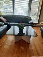 Front view of square glass-top coffee table set between sofas on hardwood floor