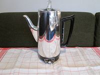 Front view of vintage chrome GE coffee percolator showing spout, black handle, glass knob lid and base dial for strength control