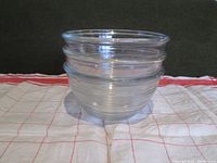Set of three clear Dominion Glass mixing bowls stacked on a cloth, showing ribs and clear glass texture.