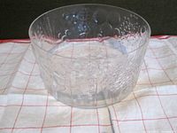 Full view of the clear glass Flora bowl showing embossed floral textures and dot patterns on the side