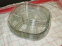 Four stacked clear glass fondue plates each divided into four sections, showing overall condition and shape.