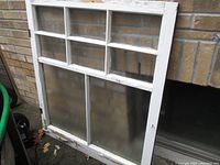 Full view of the large wood window showing six glass panels over two larger glass panels with white painted wood frame and signs of peeling paint.