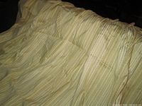 Photo of drapery panels showing wheaty and greeny striped fabric on cream background, gathered at pinch pleat tops.