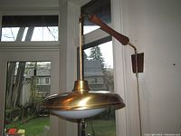 Side view of teak and brass swing arm wall light mounted to wall