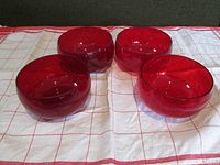 Four deep red glass bowls placed on a cloth showing color and shape.