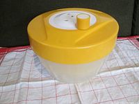 Closed salad spinner showing yellow lid and white spinning mechanism