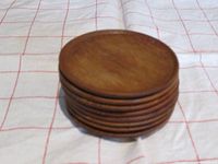 Stack of eight round teak wood coasters stacked on top of each other showing thickness and wood texture