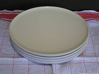 Stack of four yellow melamine plates seen from top, showing mellow yellow flat surface.