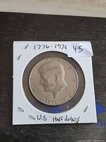 Front side of 1976 U.S. Bicentennial half dollar coin showing Kennedy's profile with dates and inscriptions.