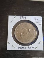 Front side of 1969 Canadian Voyageur Dollar showing the paddling voyageurs in a canoe, date, and denomination.