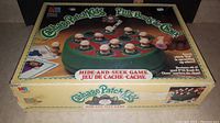 Photo of the front and top of the game box showing the green circular game base with 12 Cabbage Patch Kids figurines arranged in a circle and the game title.