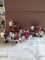 Five California Raisins figurines displayed in front of a cardboard box on a marble surface.
