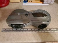 Top down photo showing the full length of the silver Legends Of Batman BatMobile toy car with visible Batman logo on hood and black wheels, measuring about 13 inches long.