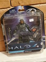 Photo of the sealed Halo 4 Master Chief action figure unopened in original packaging, showing figure, two weapons and Halo 4 branding.
