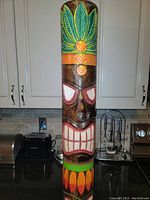 Front view of the tall totem pole showing colorful hand painted details