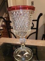 Front angle of vintage cut glass vase with diamond pattern and red rim