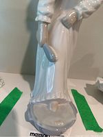 Back and side views of the glossy white porcelain figurine showing dress details, bonnet, and the umbrella held by the woman.