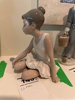 Side view of seated ballerina figurine showing profile in white tutu and dark hair in bun.