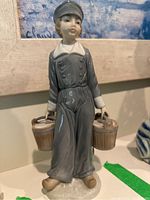 Full view of the LLADRO porcelain figurine showing the boy standing with two wooden buckets in his hands.