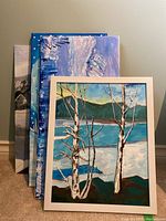 Four original paintings stacked, one framed with birch trees and lake visible on top